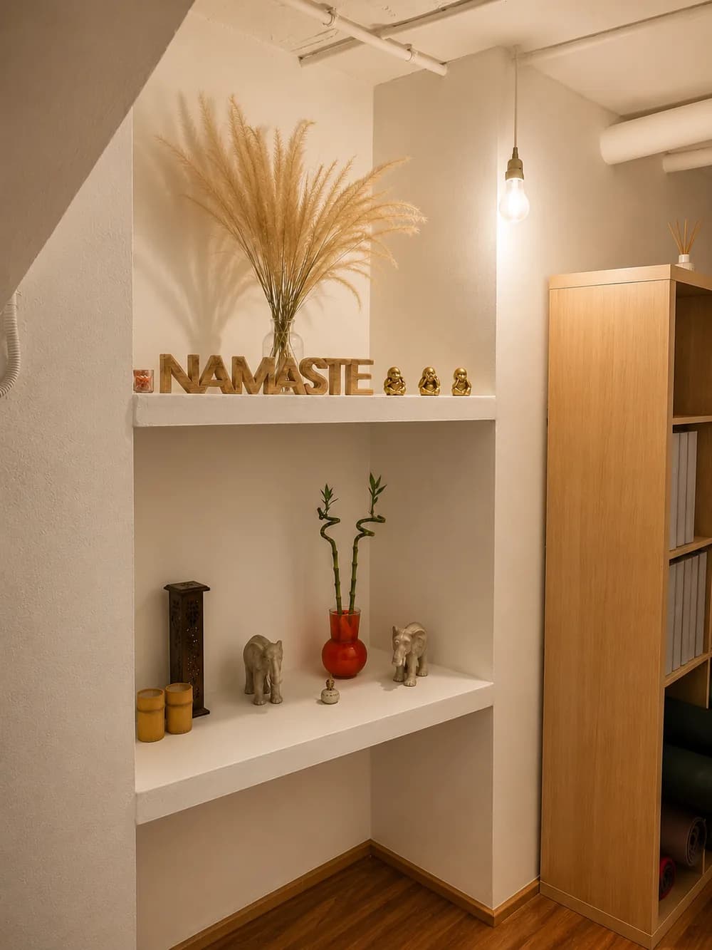Rincón de la entrada con las letras de madera NAMASTE y figuras de Buda